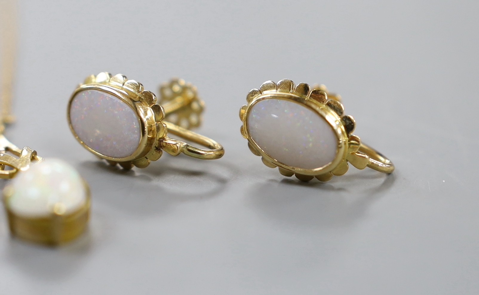 A 750 yellow metal and oval cabochon white opal set ring, size U/V, gross weight 6.2 grams, together with a pair of yellow metal and opal set ear clips and a similar pendant necklace.